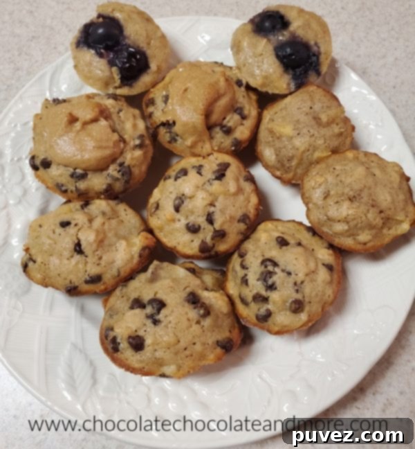 A close-up view of several freshly baked mini muffins arranged on a white plate, highlighting their golden-brown tops and various delightful additions.