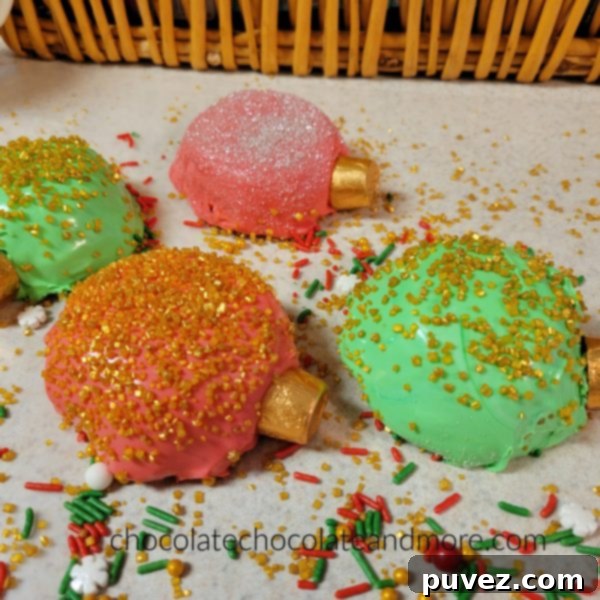 Three beautifully decorated Christmas ornament cupcakes, each with a different color scheme and sparkling sprinkles, ready to be enjoyed.