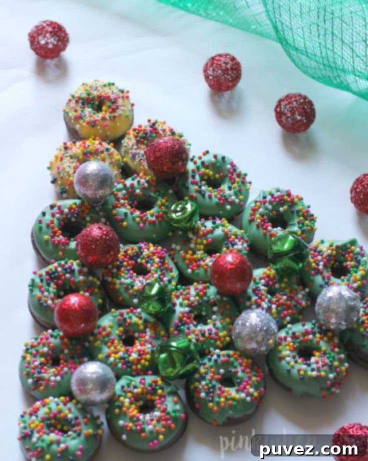 A creative Christmas tree dessert made from stacked donuts, decorated with festive icing and sprinkles.