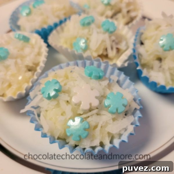 Several coconut covered snowballs on a plate with festive blue and white snowflake sprinkles, ready to be enjoyed.