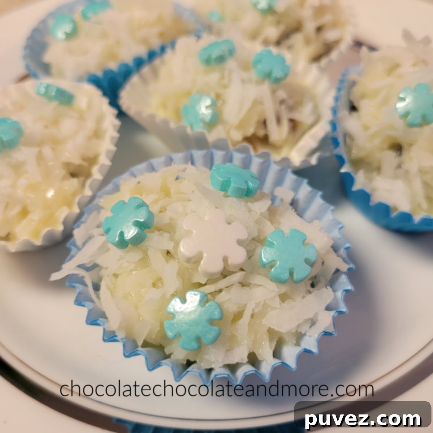 several coconut covered snowballs on a plate with blue and white snowflake sprinkles