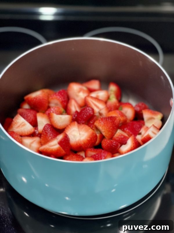Cut up fresh strawberries in a pot on the stove, beginning to simmer with a small amount of water.