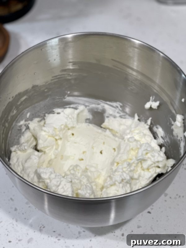Fluffy homemade whipped cream in a large mixing bowl, perfectly whipped and ready for assembly.