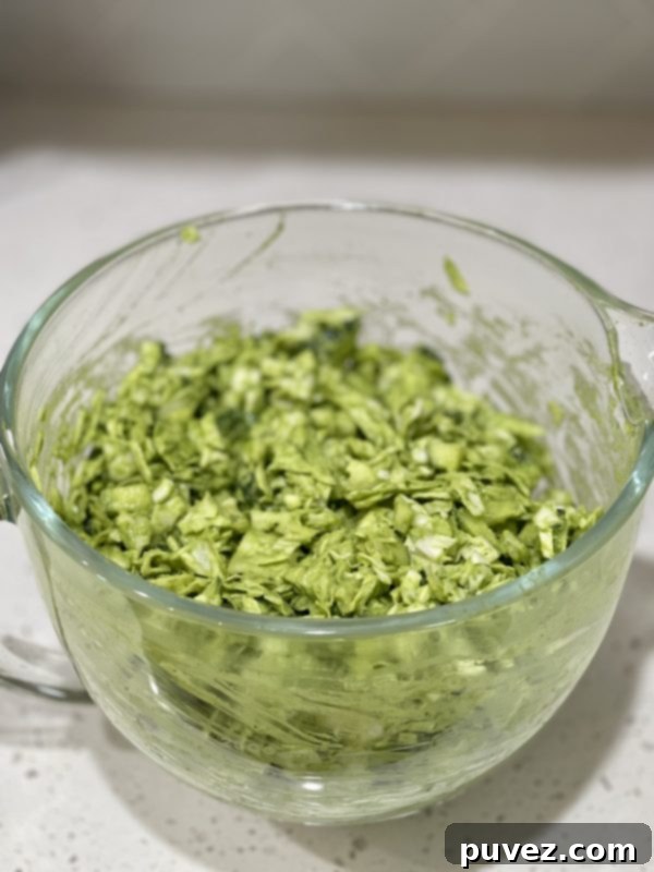 A close-up shot of the finished Green Goddess Salad, showcasing its rich green color and chunky texture in a clear glass bowl, ready for a healthy and satisfying meal.