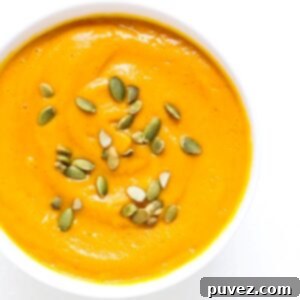 Top view of a bowl of Carrot Butternut Squash Soup topped with pumpkin seeds.