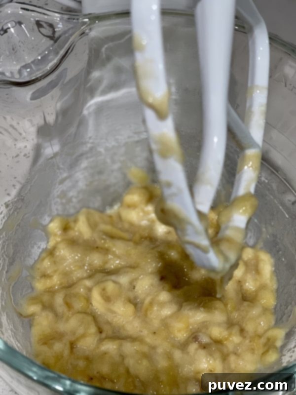 Mashed bananas in a clear mixing bowl, perfectly prepared and ready for the wet ingredients