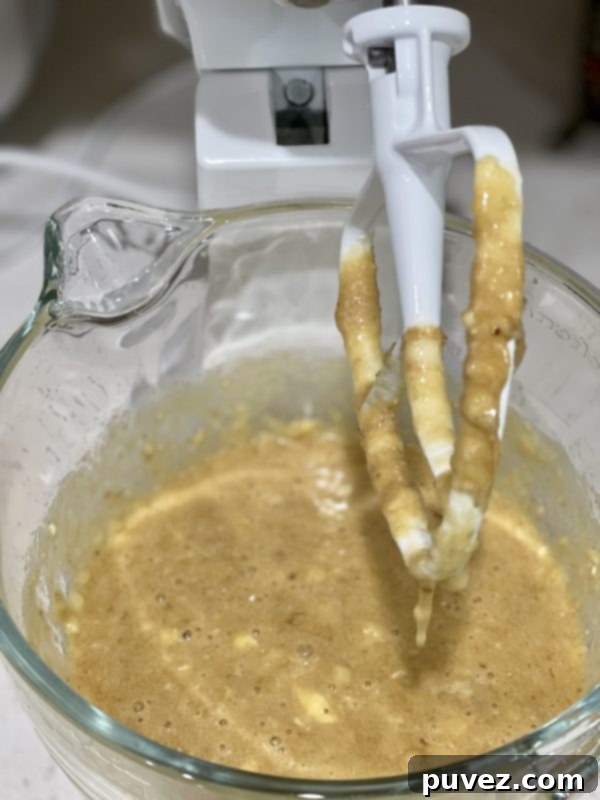 Wet ingredients expertly mixed into the mashed bananas, creating a smooth and creamy batter base