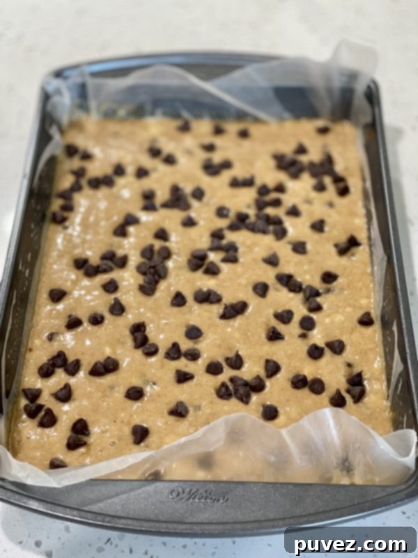 Extra chocolate chips delicately sprinkled on top of the banana bread cake batter before baking