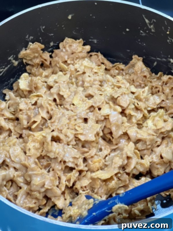 Peanut Butter Corn Flake Candy mixture in the saucepan, with corn flakes fully coated