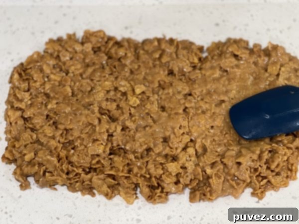 Warm Peanut Butter Corn Flake Candy spread onto wax paper for shaping