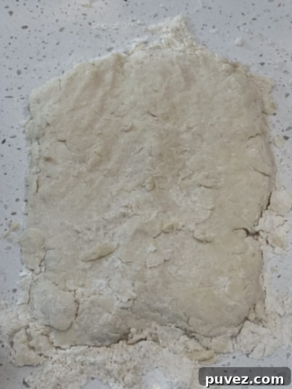 Biscuit dough shaped into a rectangle on a floured surface, ready for folding