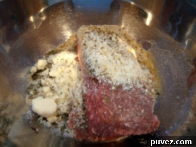 A hand gently mixing ground beef with breadcrumbs, egg, and herbs in a large bowl to prepare the meatball mixture.