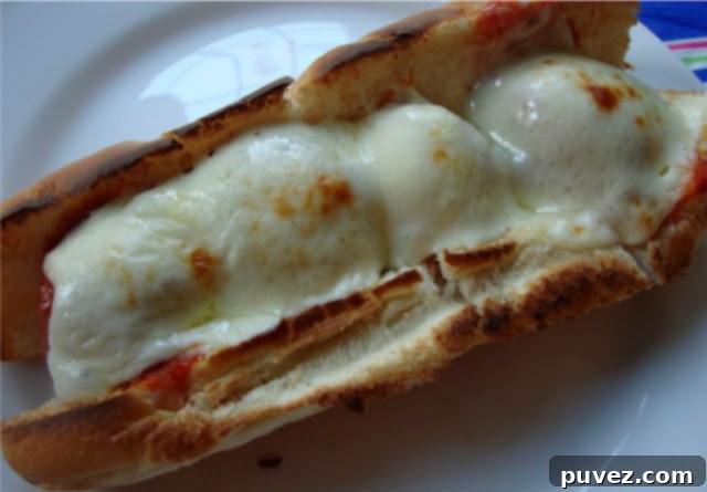 A finished, broiled meatball sub with beautifully melted provolone or mozzarella cheese, ready to be enjoyed.