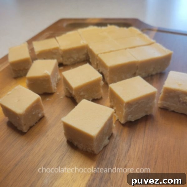 Close-up of neatly arranged squares of peanut butter fudge on a wooden cutting board, ready for serving.