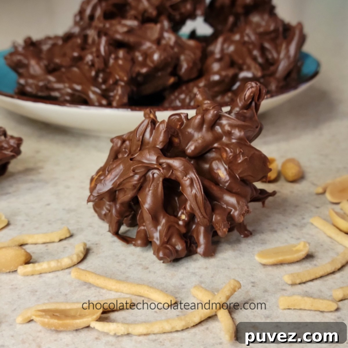 A single chocolate haystack presented elegantly in front of a platter full of more haystacks, ready to be enjoyed.
