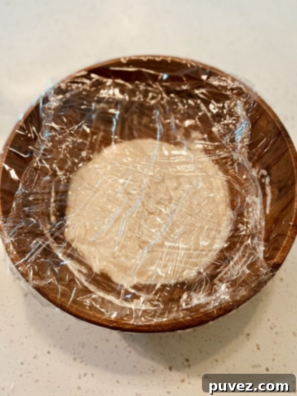 dough in a large wooden bowl with the cling wrap on before rising