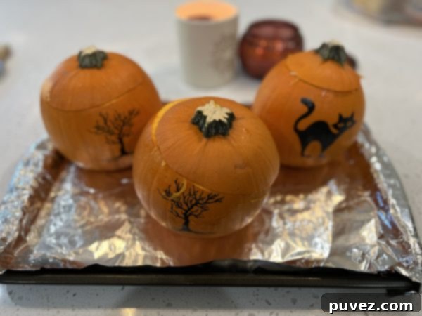 3 pumpkins sitting on a baking sheet lined with aluminum foil
