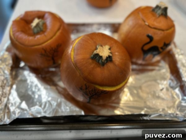 3 pumpkins after coming out the oven sitting on a baking sheet lined with aluminum foil 