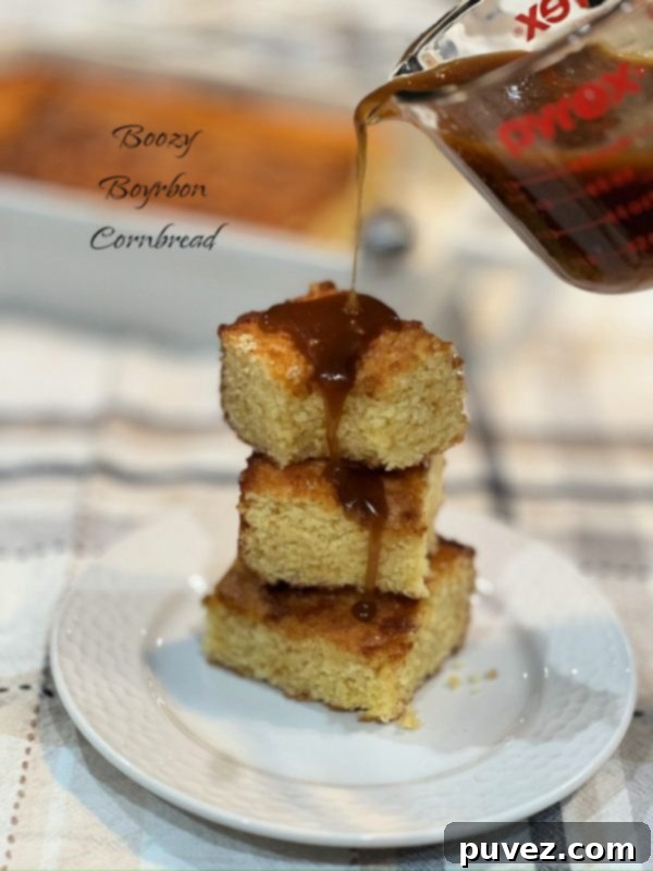 Moist Boozy Bourbon Cornbread, drizzled with a rich bourbon maple glaze, on a white serving platter.