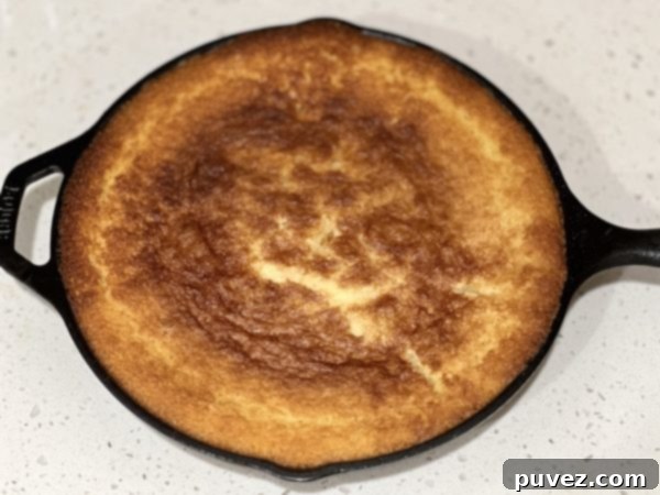 Freshly baked Boozy Bourbon Cornbread cooling in a cast iron skillet.