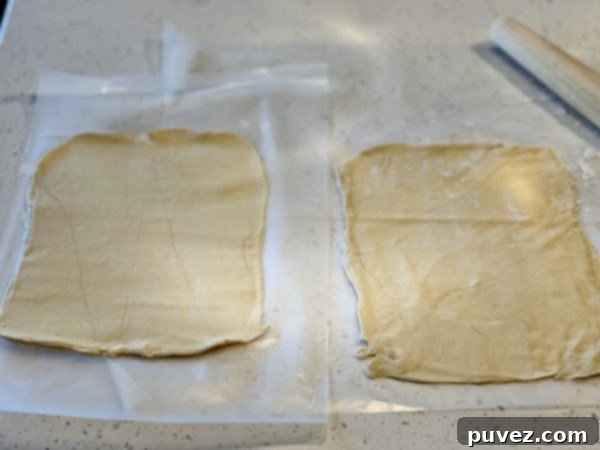 Crescent roll dough neatly rolled out into a smooth rectangle on parchment paper, ready for the Nutella filling.