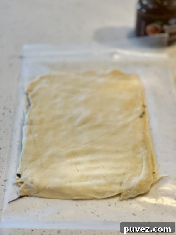 Two layers of crescent roll dough, with Nutella spread in between, carefully stacked on parchment paper, forming the base for the Christmas tree.