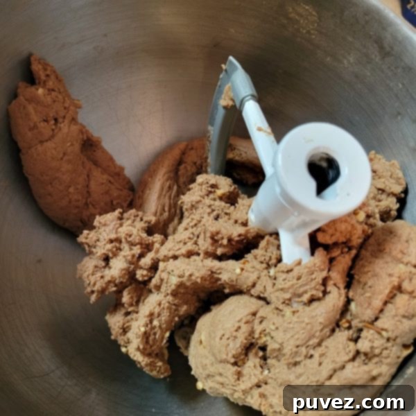 Close-up of raw cookie dough, visibly thick and ready to be rolled into individual portions, resting on a clean surface.