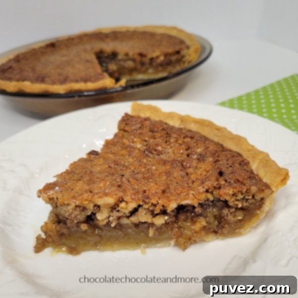 a slice of pecan pie on a white plate in front of a cut pie.