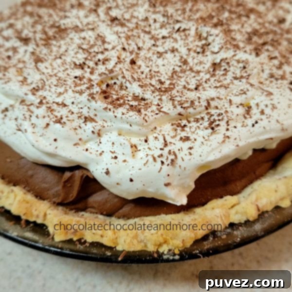 A close-up view of a whole chocolate French Silk Pie, before the addition of its luxurious whipped cream topping, showcasing its smooth surface.