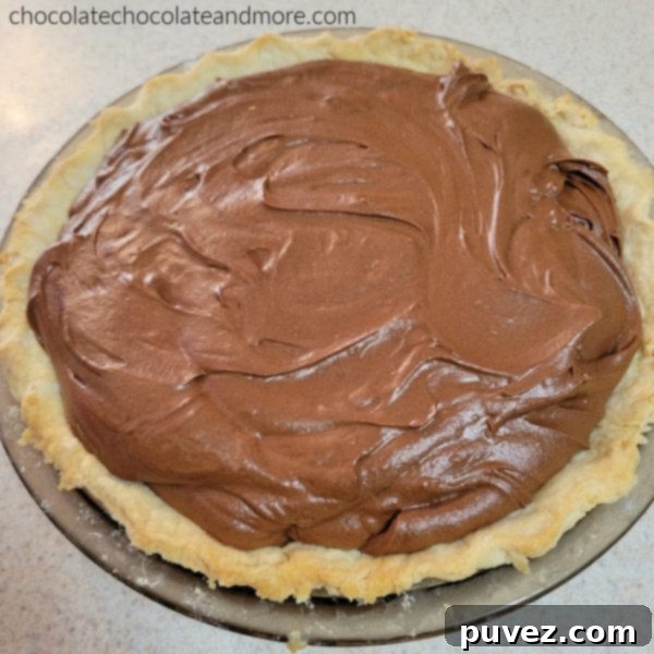 A whole chocolate pie before being topped with whipped cream, showing the deep, rich color of the filling.