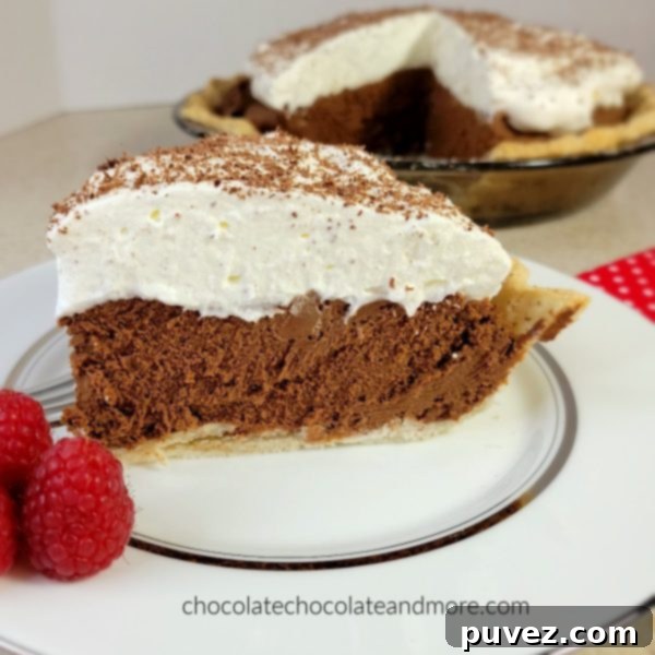 A slice of French Silk Pie on a white plate with the rest of the pie in the background, beautifully presented.