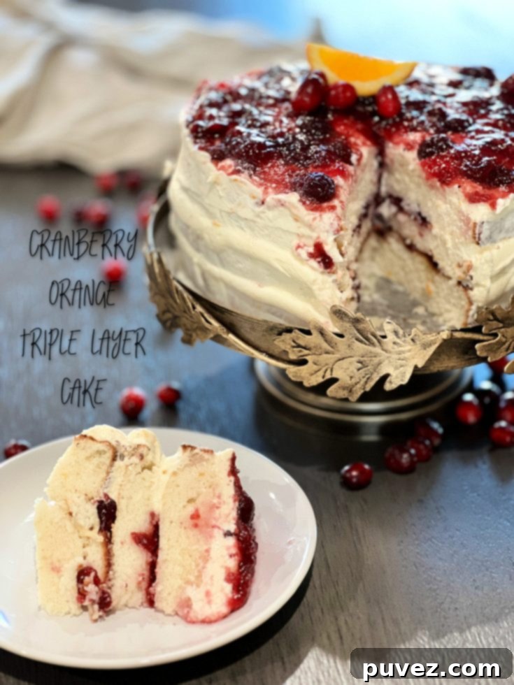 A beautifully decorated Cranberry Orange Triple Layer Cake on a white cake stand.