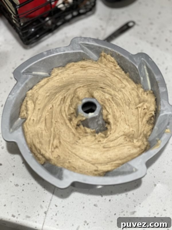 Cake batter spread evenly into a greased bundt pan