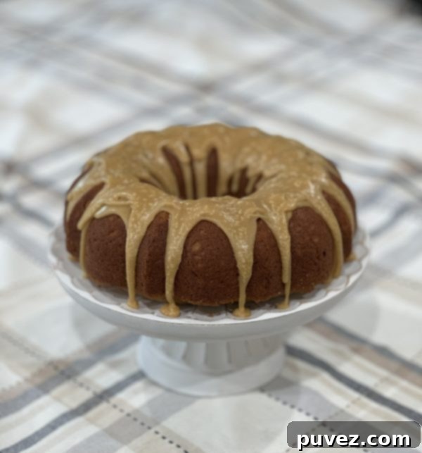 Beautiful Butterscotch Bundt Cake with glaze on a white cake stand