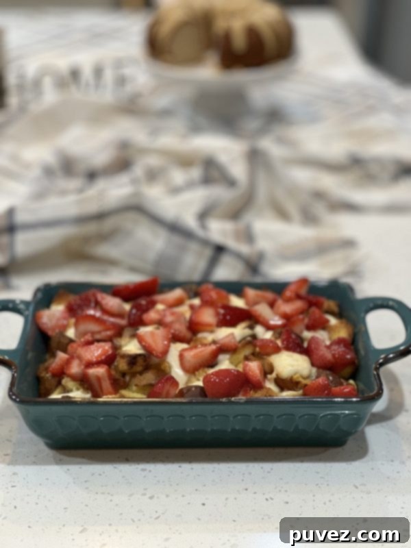 A freshly baked Strawberries and Cream French Toast Casserole, topped with vibrant macerated strawberries