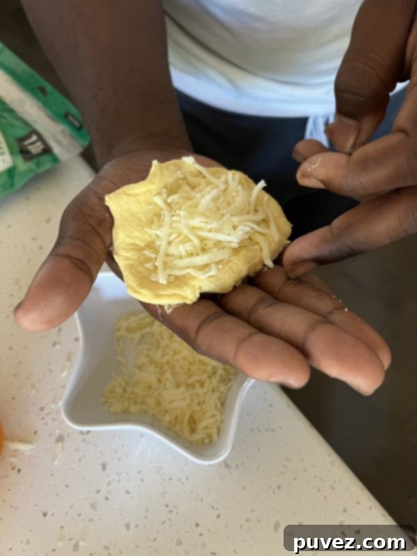 Flattened biscuit dough with cheese filling, ready to be folded into a bomb.