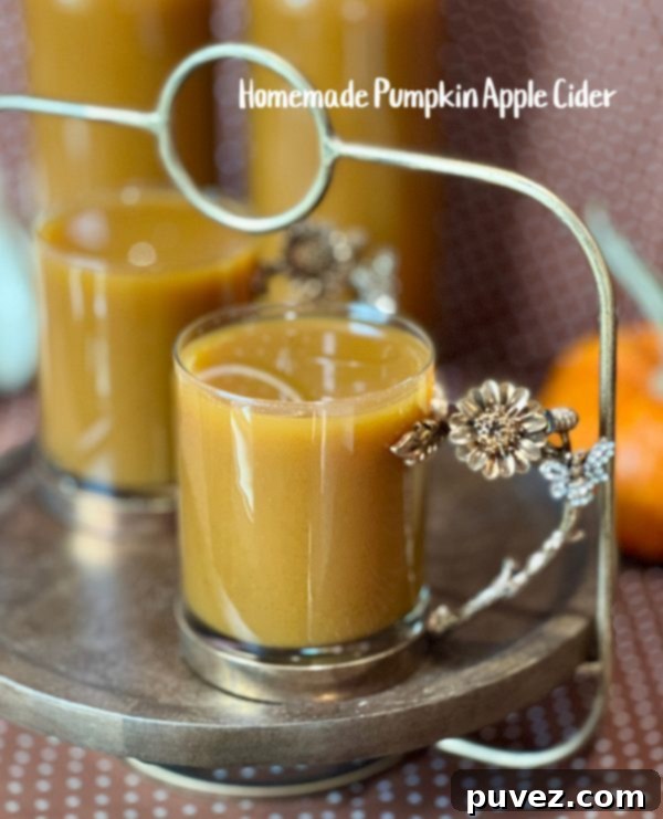 Homemade Pumpkin Apple Cider, a perfect fall beverage served in a mug with apple slices and cinnamon sticks, surrounded by autumn decor.