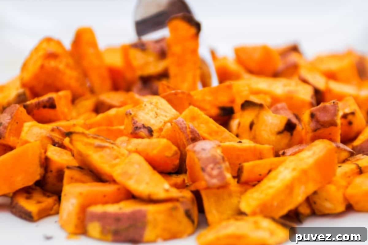 Roasted sweet potato chunks on a white plate, showcasing their golden-brown edges.