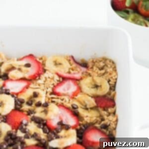 Banana baked oatmeal with strawberries and chocolate chips in a white baking dish.