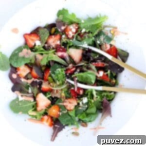 Strawberry Goat Cheese Salad in a large white serving bowl with tongs.