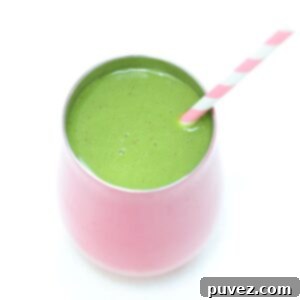 Spinach mango smoothie in a pink tumbler with a pink and white striped straw.