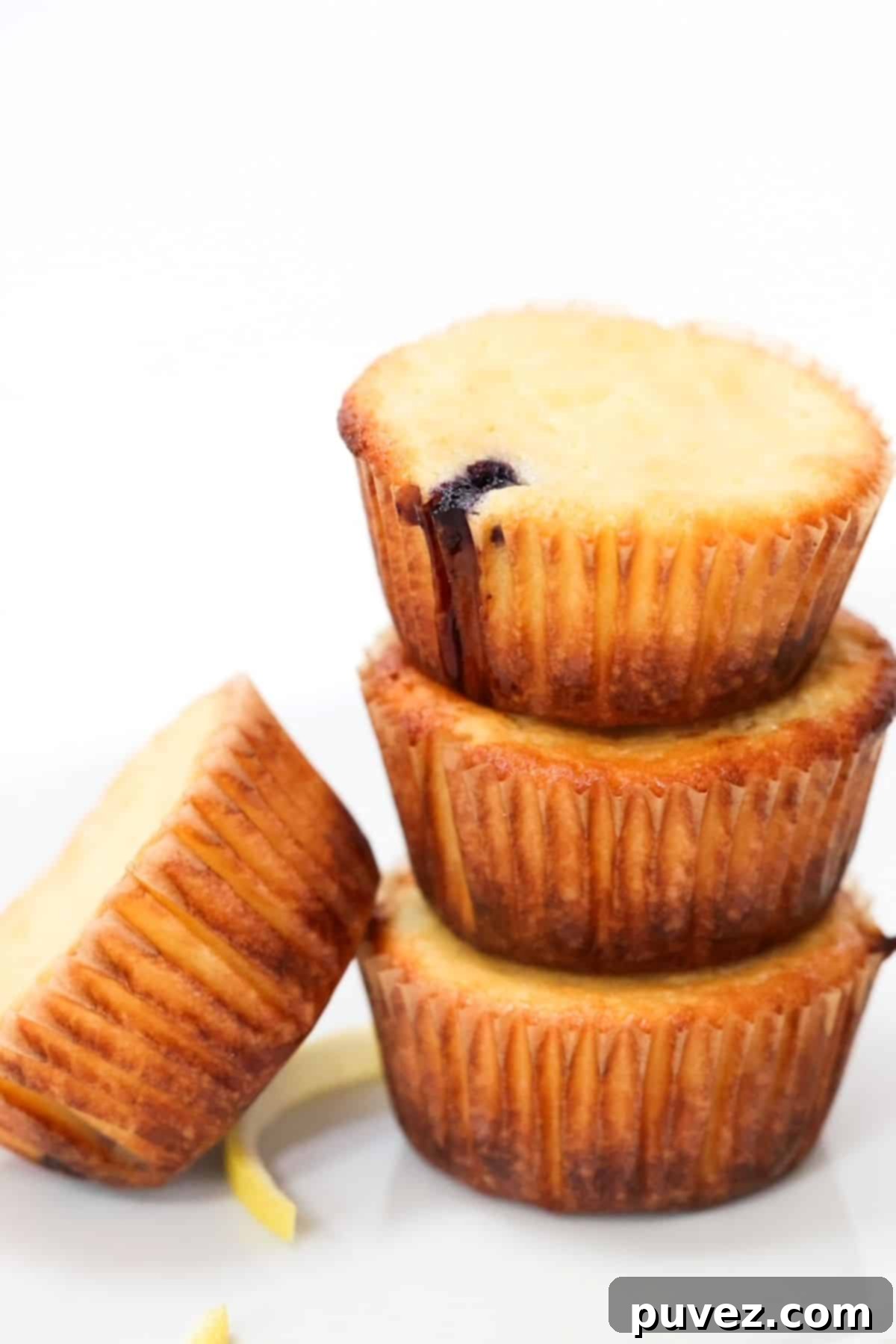 Three lemon yogurt muffins stacked with a fourth muffin leaning on the left side of the stack.