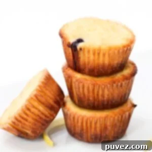 Four stacked lemon yogurt muffins with pieces of lemon peel at the base.