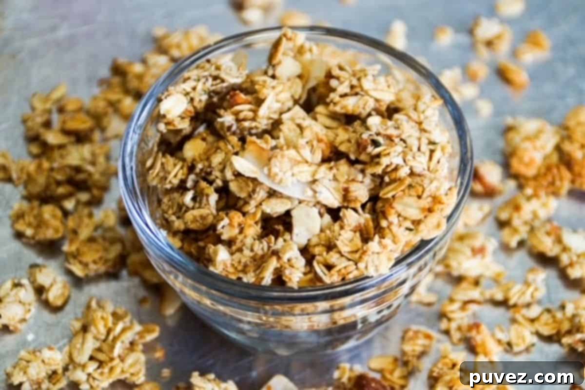 Golden-brown, clustered granola served in an elegant glass dish, ready to be enjoyed.
