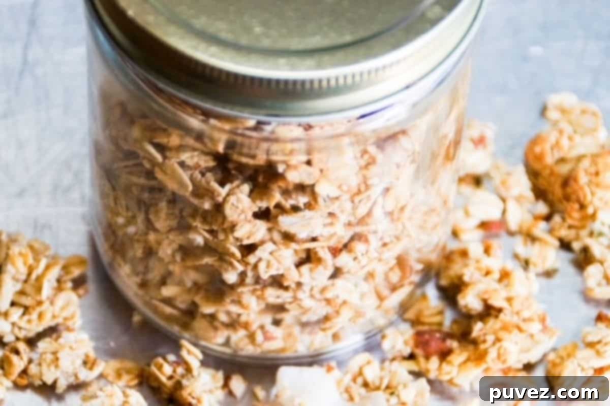 Freshly made crunchy granola, stored neatly in an elegant mason jar, ready to be gifted or enjoyed as a delightful snack.