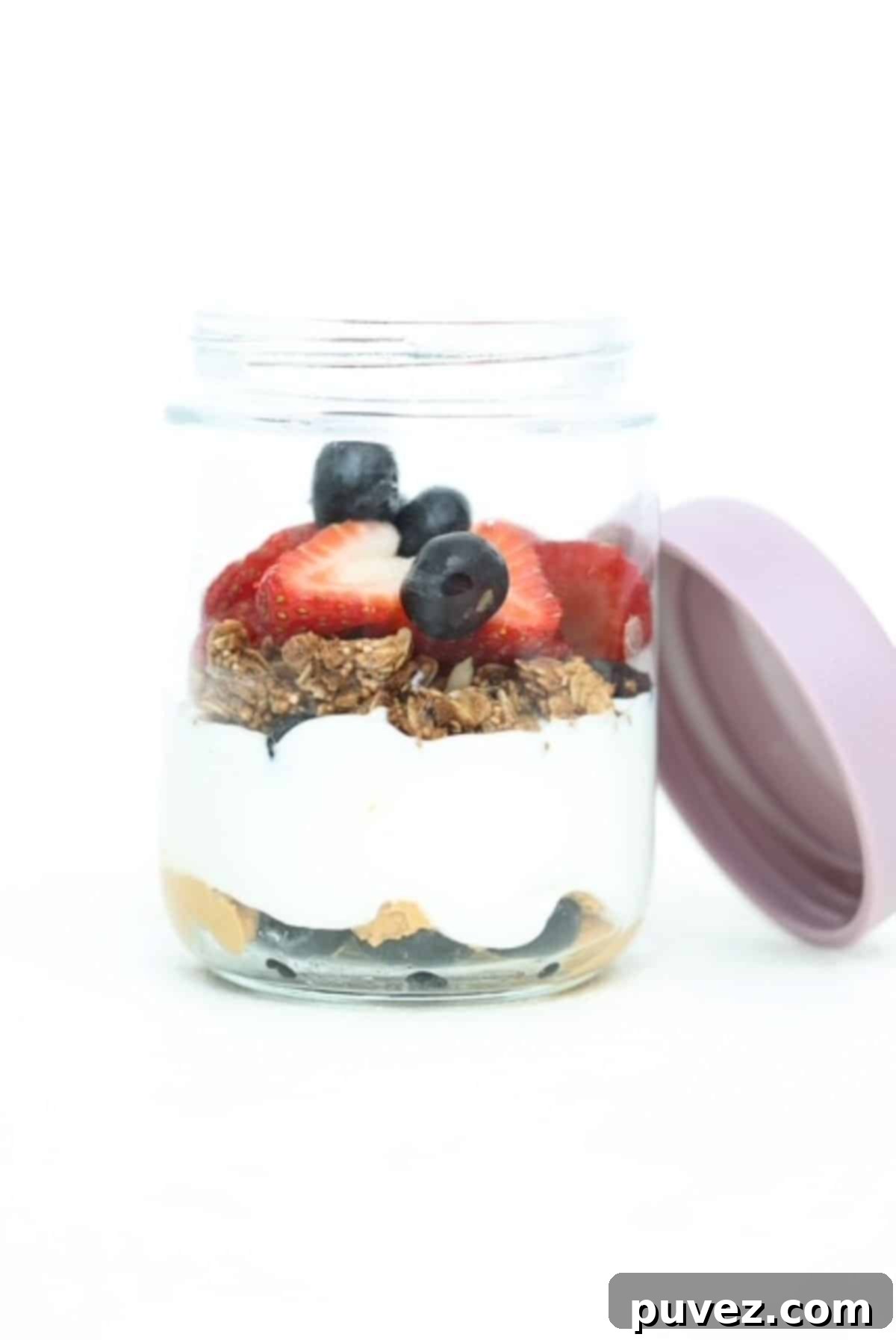 Yogurt parfait with a layers of peanut butter, Greek yogurt, granola and berries in a glass jar.