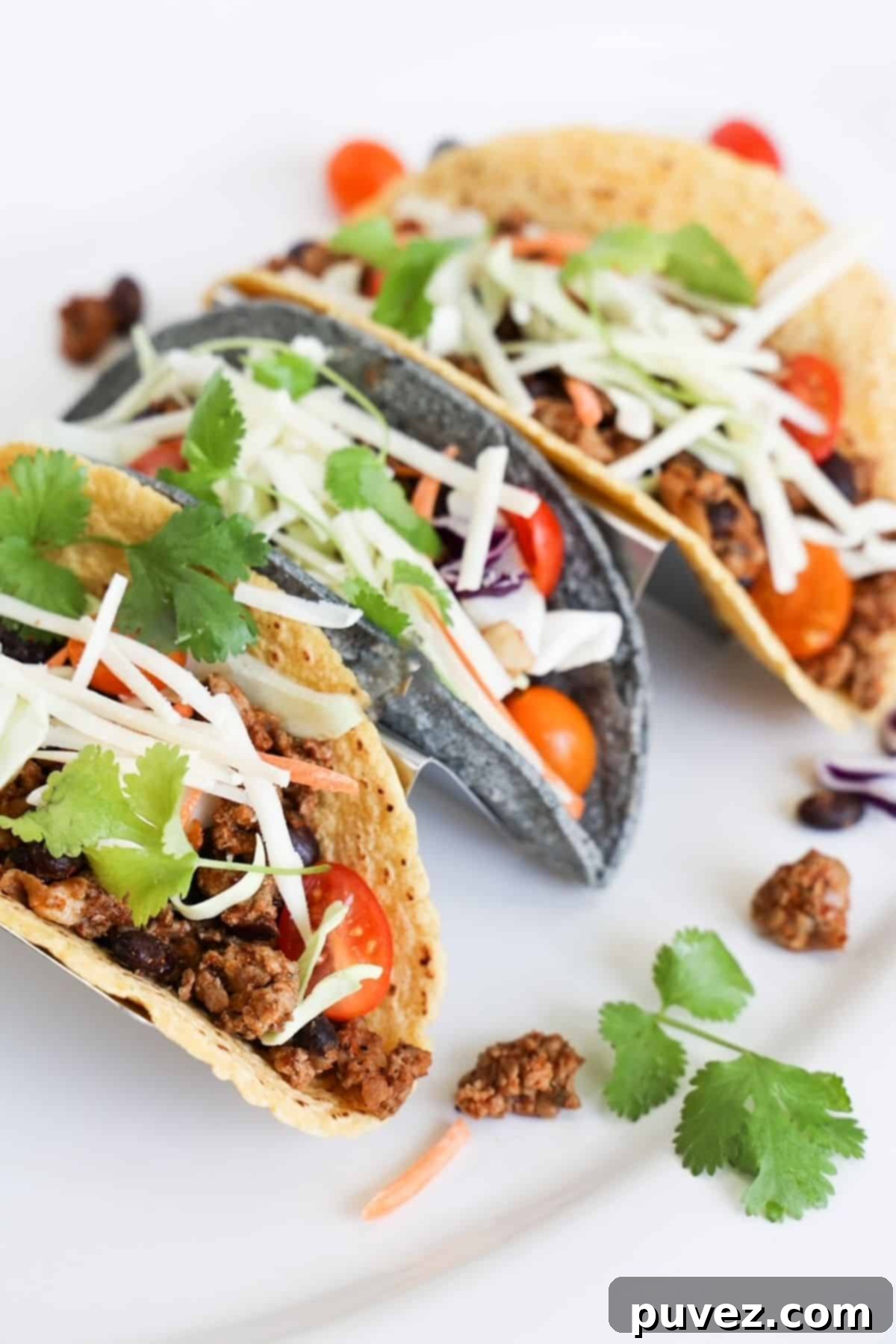 Three ground turkey tacos in a taco holder on white platter.