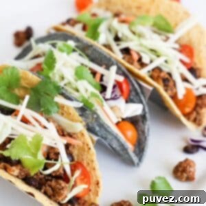 Three ground turkey tacos in a taco holder on a white platter.