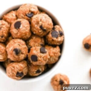 Top view of one white bowl filled with bliss balls. A few bliss balls are to the right of the bowl.