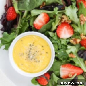 Effortless Mango Salad Dressing 5 Sweet mango salad dressing topped with hemp hearts, served alongside a colorful strawberry salad on a clean white plate.